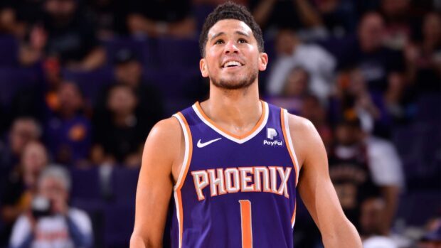 Devin Booker smiles during a basketball game wearing a Phoenix Suns jersey, HD Desktop Wallpaper