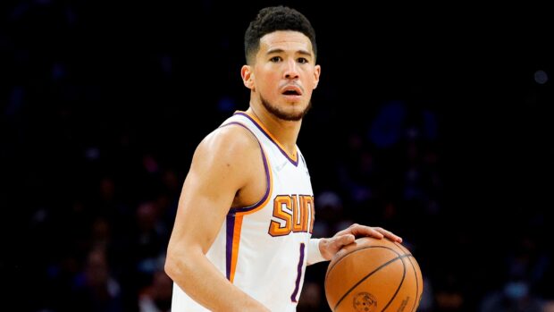 Devin Booker is focused holding a basketball on the court, HD Desktop Wallpaper