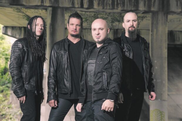 The Disturbed band members stand confidently in leather jackets under a concrete structure, HD Desktop Wallpaper