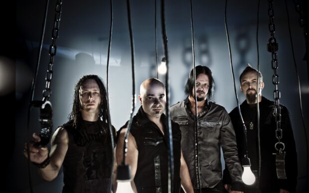The Disturbed band members are standing behind hanging chains in a dimly lit room, 2K Desktop Wallpaper