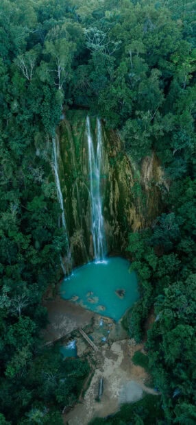 A tall waterfall flows into a turquoise pool surrounded by dense Dominican Republic greenery, 2K Mobile Wallpaper