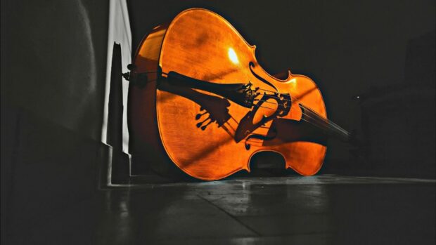 A double bass rests against a dark background with warm lighting highlighting its wooden texture, HD Desktop Wallpaper
