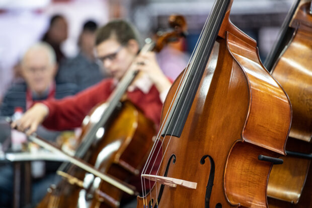 A close up view of a double bass being played in a music rehearsal with musicians in the background, HD Desktop Wallpaper
