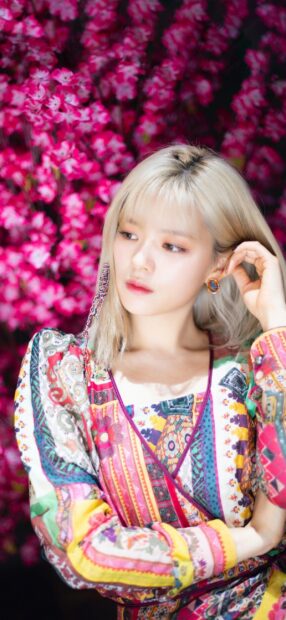 A portrait of Jeongyeon Twice wearing a colorful patterned dress with vibrant pink blossoms behind her, 2K Mobile Wallpaper