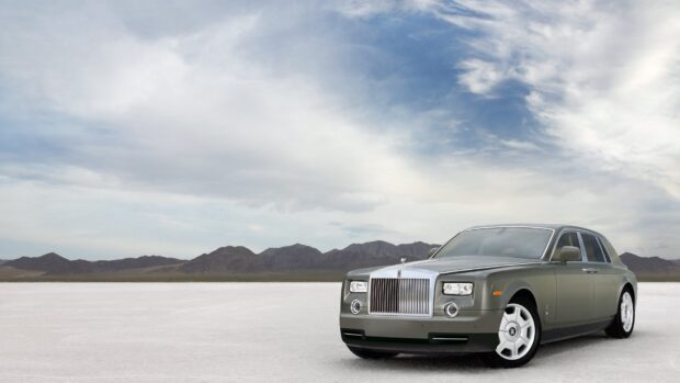 A Rolls Royce Phantom stands alone on a vast desert with mountains and cloudy sky behind it, HD Desktop Wallpaper