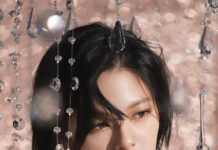 Shiny crystal chandelier earrings and necklace worn by a woman with short black hair, elegant off-the-shoulder ruffled top, and a glamorous, luxury fashion style.