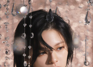 Shiny crystal chandelier earrings and necklace worn by a woman with short black hair, elegant off-the-shoulder ruffled top, and a glamorous, luxury fashion style.