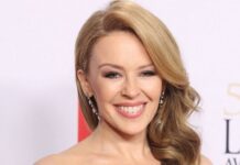 Kylie Minogue shows an elegant smile with wavy blonde hair at an award event, HD Desktop Wallpaper