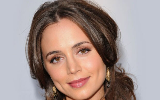 Close up of Eliza Dushku with brown eyes and styled hair wearing gold earrings