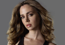 Eliza Dushku with wavy hair posing against gray background