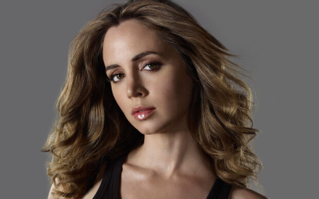 Eliza Dushku with wavy hair posing against gray background