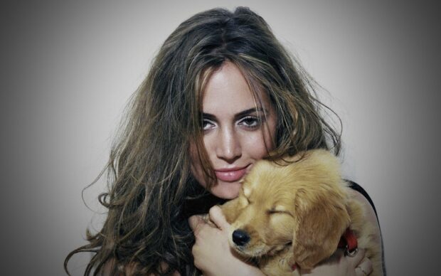 Eliza Dushku holding a golden retriever puppy in a warm embrace