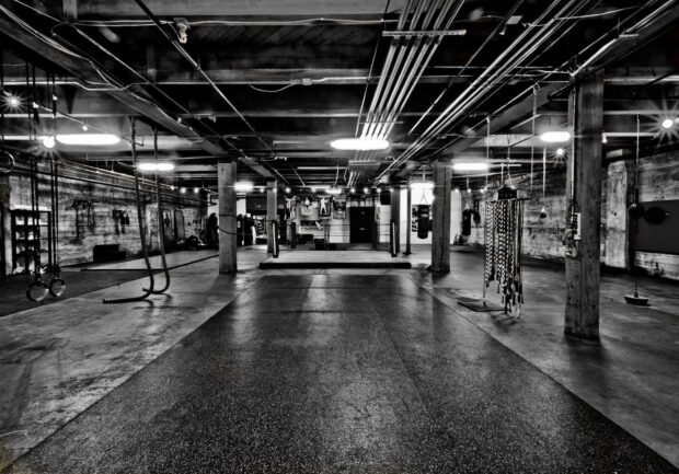 An empty Crossfit gym with workout equipment and ropes hangs in a spacious area, HD Desktop Wallpaper