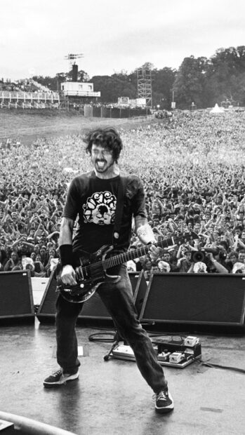 A Foo Fighters guitarist joyfully plays in front of a large crowd during a live concert, HD Phone Wallpaper