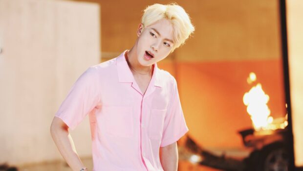 Jin wears a pink shirt while looking surprised near a fire, HD Desktop Wallpaper