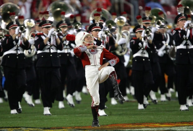 A marching band member leads a lively performance with brass instruments on a football field, 2K Desktop Wallpaper
