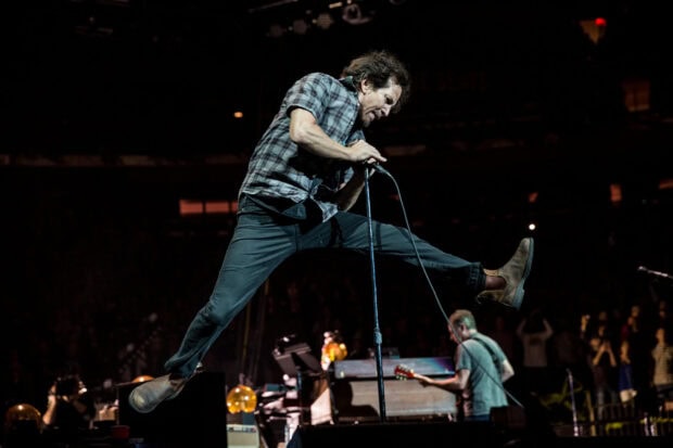 A Pearl Jam singer jumps while holding a microphone during a live concert, HD Desktop Wallpaper