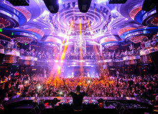 A DJ performs in front of a large crowd enjoying the vibrant nightclub atmosphere, HD Desktop Wallpaper