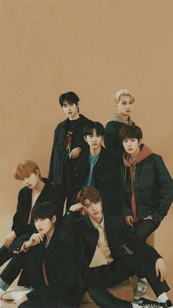 A group of Enhypen members pose together against a warm brown background in stylish outfits, HD Mobile Wallpaper