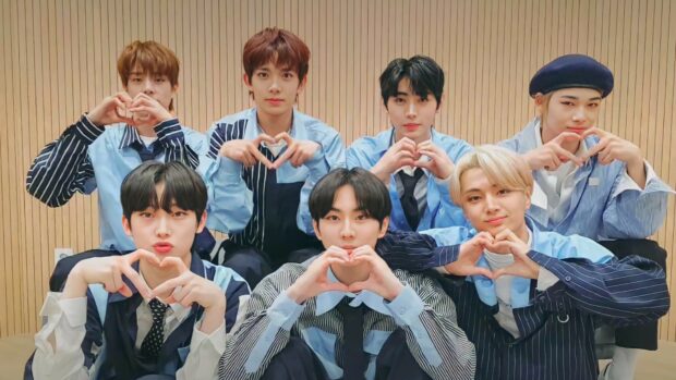 Seven members making heart shapes with their hands in a casual setting, HD Desktop Wallpaper