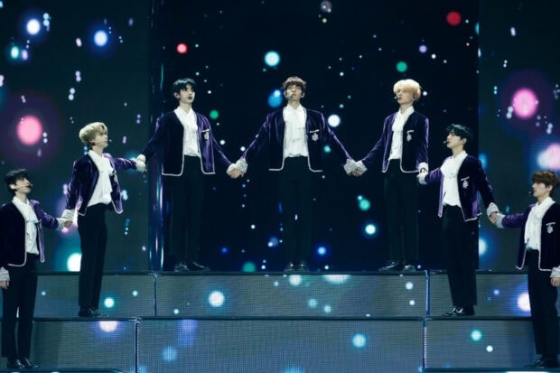 Enhypen members are holding hands during a stage performance with light effects, HD Desktop Wallpaper