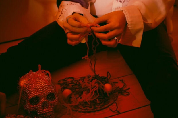 A person is creating tangled yarn art with beads near a glitter skull, HD Mobile Wallpaper