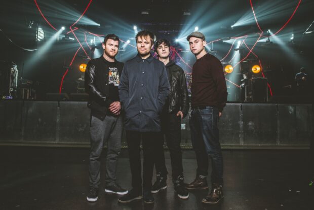 Enter Shikari Band posing in front of a stage with bright lights and equipment, HD Desktop Wallpaper