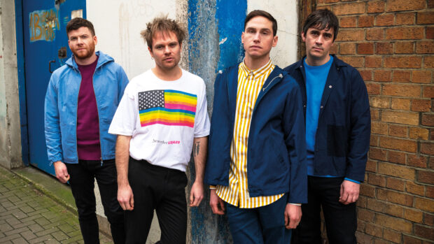 The Enter Shikari band members are standing outdoors near a brick wall and blue door, HD Desktop Wallpaper