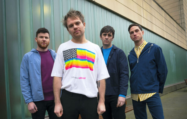 Enter Shikari band members stand against a green wall in casual clothes, HD Desktop Wallpaper