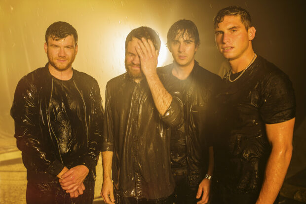The Enter Shikari band members are wet and standing under yellow lighting, 2K Desktop Wallpaper