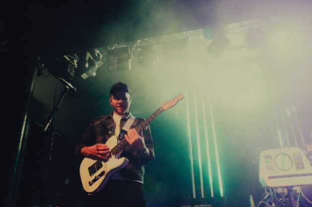 A guitarist from Enter Shikari plays on stage with dynamic lighting behind, HD Desktop Wallpaper