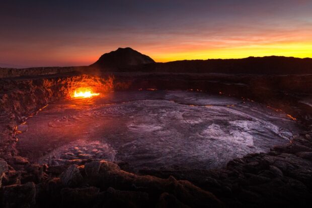 The Ethiopia volcanic lava emits glowing heat under a vibrant sunset sky, HD Desktop Wallpaper