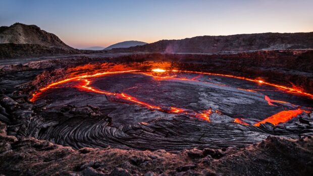 The Ethiopia Wallpapers feature a glowing volcanic lava lake surrounded by rocky terrain at sunset, HD Desktop Wallpaper