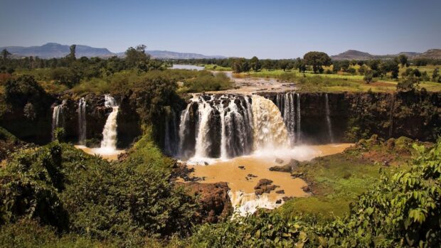 A beautiful view of a waterfall surrounded by lush greenery and hills in Ethiopia, HD Desktop Wallpaper