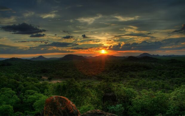 The Ethiopian landscape features a vibrant sunset over green hills and scattered clouds, 2K Desktop Wallpaper