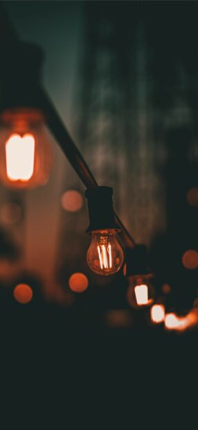 Warm glowing fairy lights hanging in a dark blurred background