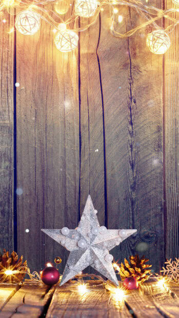 Silver star decoration with fairy lights and pine cones on wooden surface