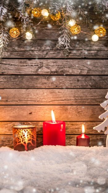 Warm fairy lights and lit candles on snow with wooden background