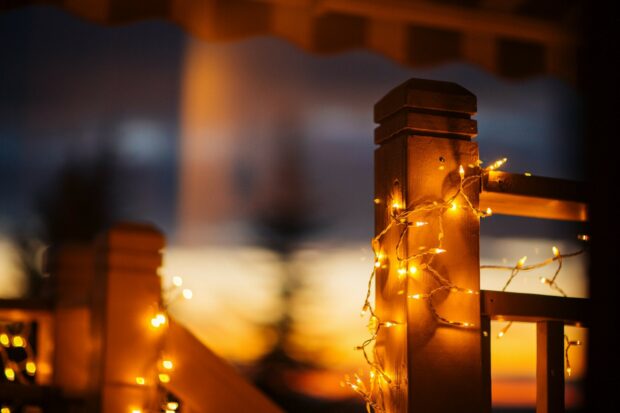 Warm fairy lights wrapped around wooden railing during sunset light