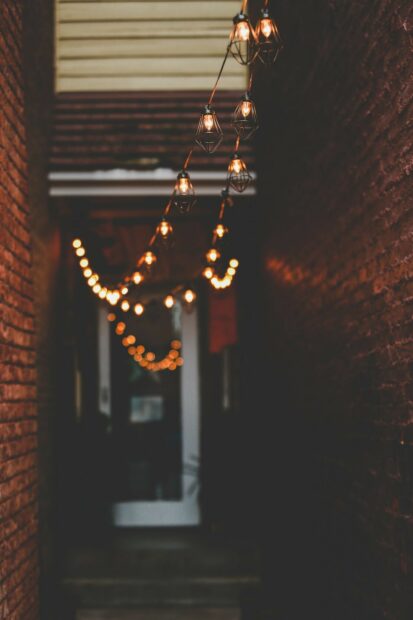 Warm fairy lights hanging between brick walls in a narrow alleyway