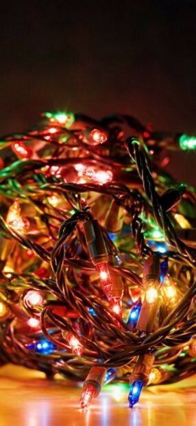 A close up of colorful fairy lights tangled together on a wooden surface