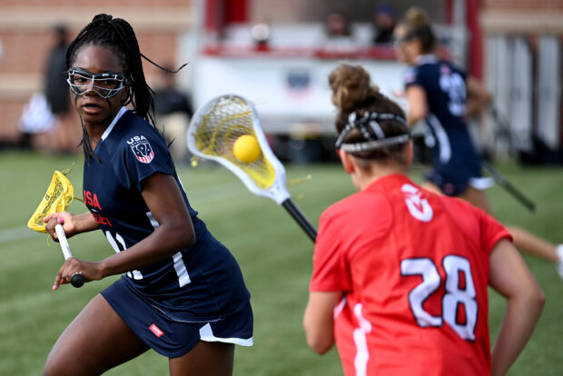 A female lacrosse player in navy blue jersey dodges an opponent while holding the lacrosse stick, 2K Desktop Wallpaper