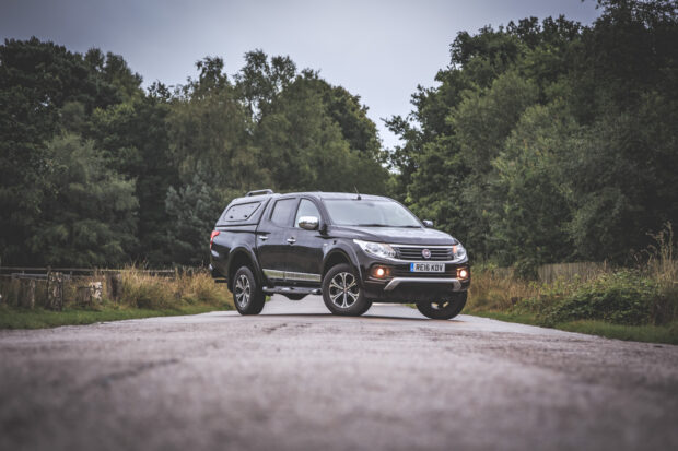 A black Fiat Fullback is driving along a country road surrounded by green trees, HD Desktop Wallpaper