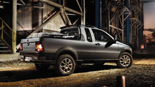 A Fiat Fullback trekking truck is parked in an industrial area at night with lights illuminating the scene, HD Desktop Wallpaper