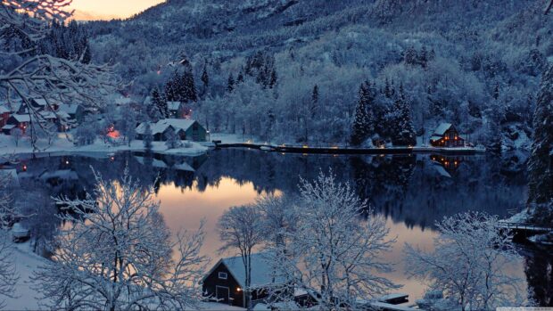 Snow covered houses and trees reflect on a calm lake in a Finland winter landscape