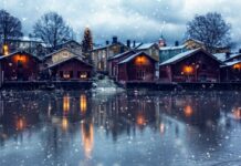 Snowfall over wooden houses near frozen water in Finland