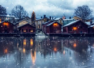Snowfall over wooden houses near frozen water in Finland