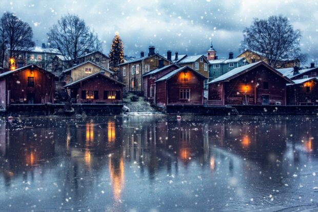 Snowfall over wooden houses near frozen water in Finland