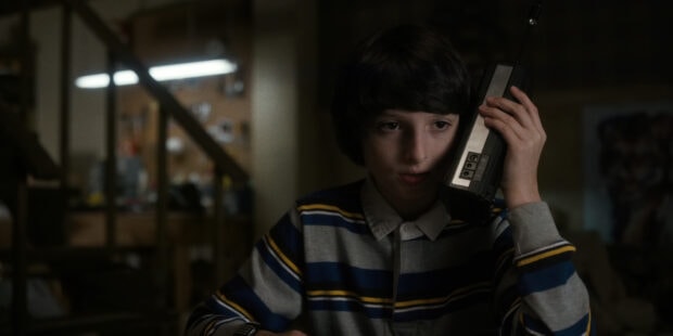 A young Finn Wolfhard holds a vintage walkie talkie while looking attentive, 4K Desktop Wallpaper