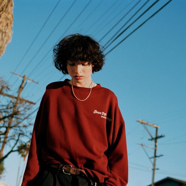 Finn Wolfhard is wearing a red sweater under a clear blue sky, HD Desktop Wallpaper